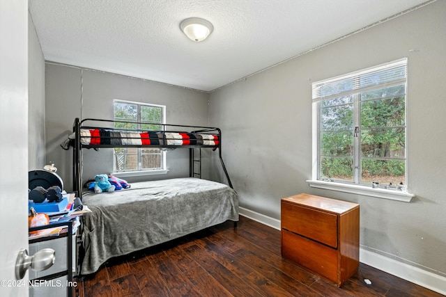 bedroom featuring a textured ceiling, dark hardwood / wood-style floors, and multiple windows