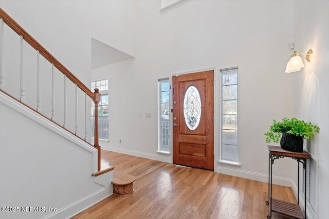 entryway with a towering ceiling and light wood-type flooring