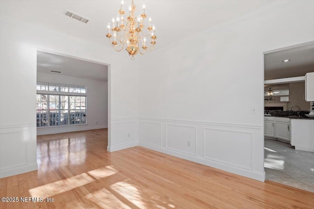 unfurnished dining area with ceiling fan with notable chandelier, light hardwood / wood-style floors, and sink