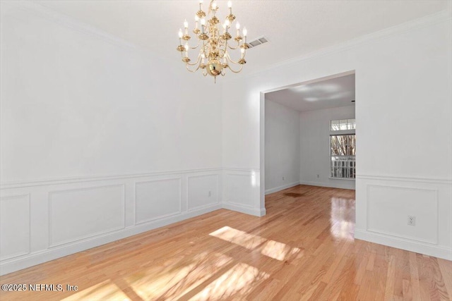 unfurnished dining area with a notable chandelier, crown molding, and light hardwood / wood-style flooring