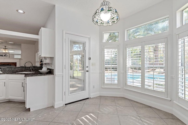 doorway to outside with ceiling fan, sink, and light tile patterned floors