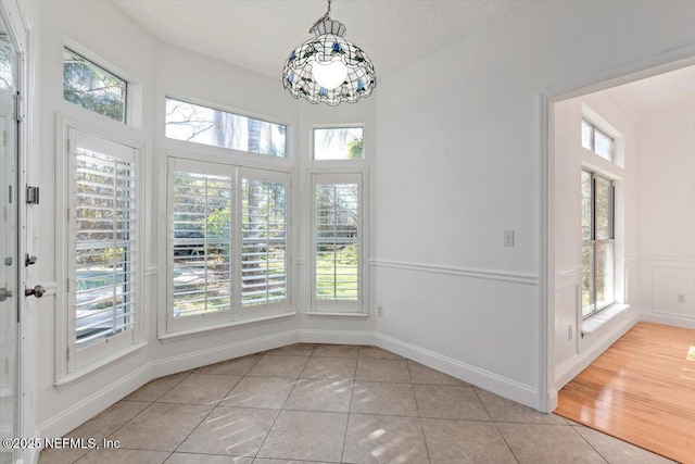 unfurnished dining area with a textured ceiling and light tile patterned flooring