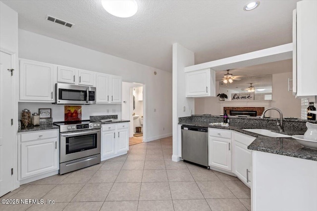 kitchen featuring dark stone countertops, white cabinetry, ceiling fan, and appliances with stainless steel finishes