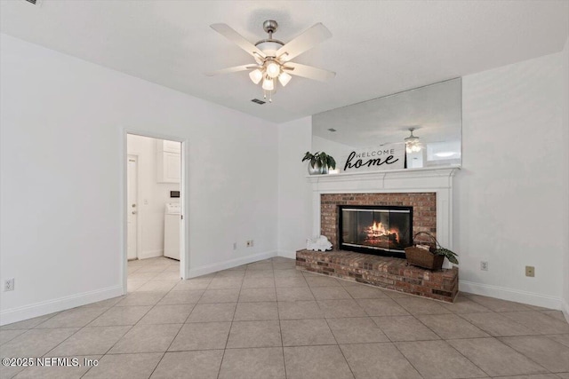 tiled living room with washer / clothes dryer, ceiling fan, and a brick fireplace