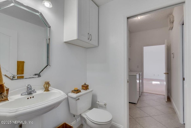 bathroom with tile patterned floors, sink, toilet, a textured ceiling, and washer / dryer