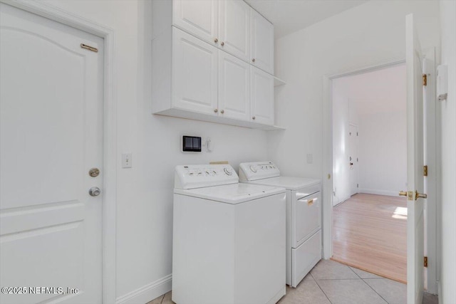 laundry area featuring cabinets, washing machine and dryer, and light tile patterned flooring