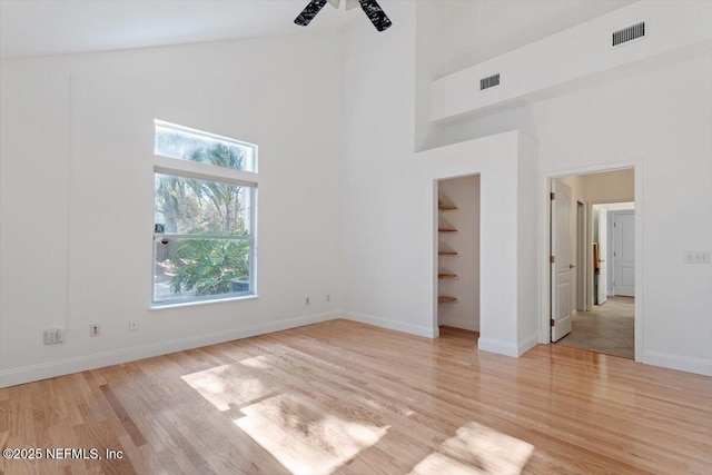 unfurnished room featuring ceiling fan, light wood-type flooring, and a high ceiling