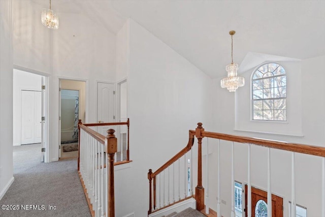 stairs with carpet flooring, lofted ceiling, and a notable chandelier