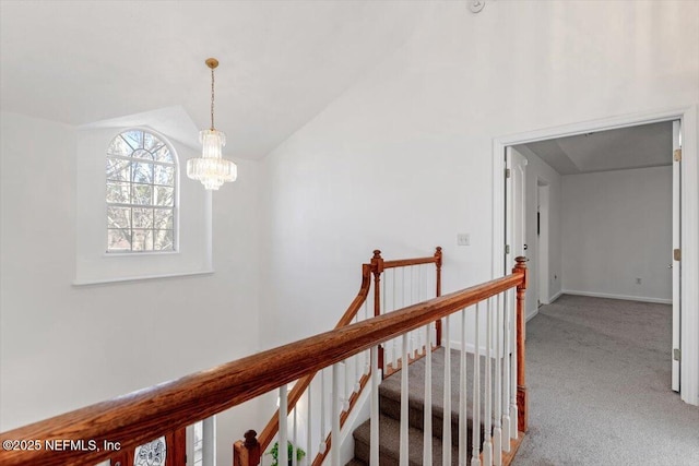 hallway featuring carpet, vaulted ceiling, and an inviting chandelier