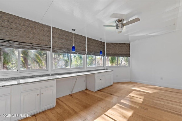 kitchen with decorative light fixtures, white cabinetry, ceiling fan, and light hardwood / wood-style flooring