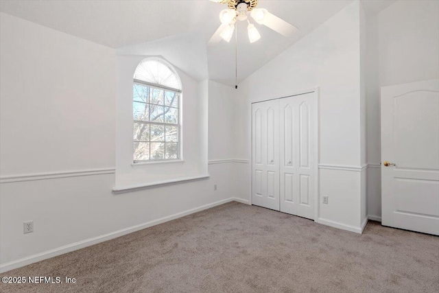 unfurnished bedroom with ceiling fan, a closet, light carpet, and vaulted ceiling