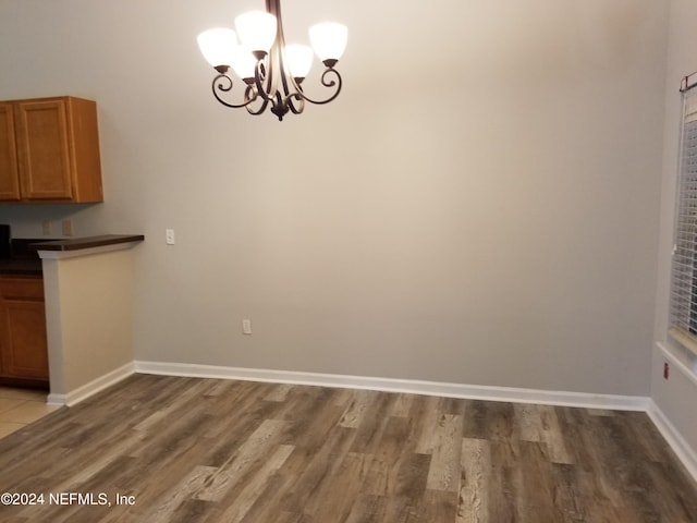 unfurnished dining area with hardwood / wood-style floors and a notable chandelier