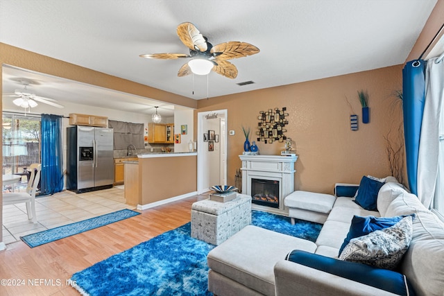 living room featuring light wood-type flooring, ceiling fan, and sink