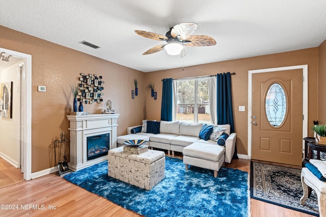 living room featuring ceiling fan, hardwood / wood-style floors, and a textured ceiling