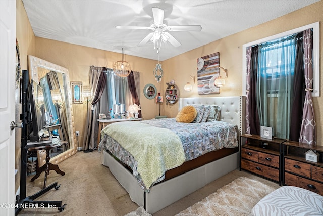 carpeted bedroom featuring a textured ceiling and ceiling fan with notable chandelier