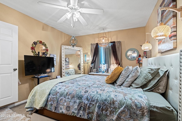 bedroom featuring ceiling fan with notable chandelier