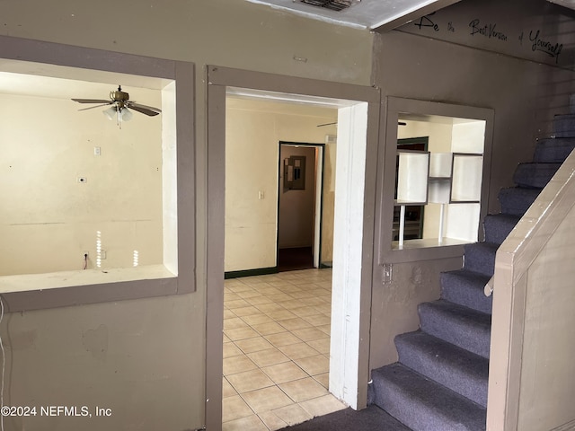 staircase featuring tile patterned floors and ceiling fan