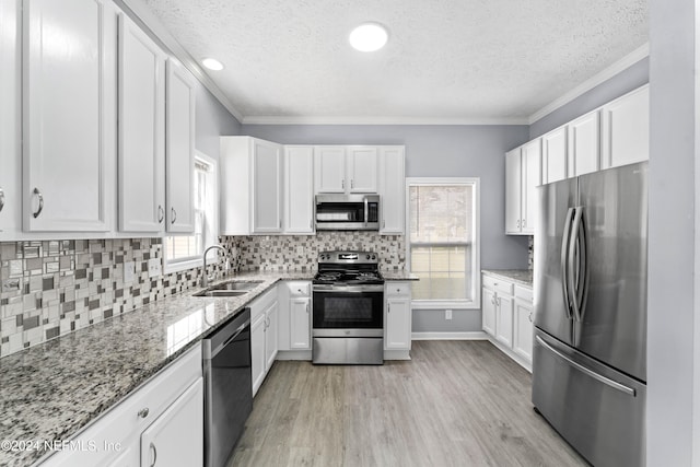 kitchen with light stone counters, sink, white cabinets, and appliances with stainless steel finishes