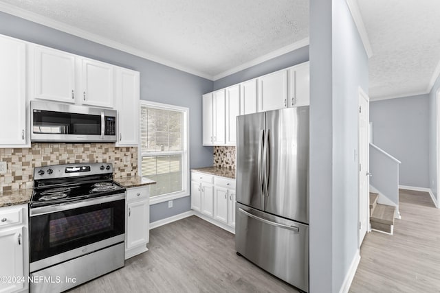 kitchen with decorative backsplash, appliances with stainless steel finishes, white cabinetry, and dark stone counters