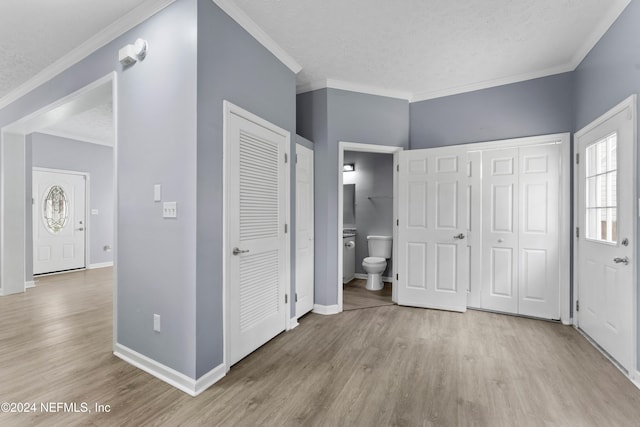 unfurnished bedroom featuring light hardwood / wood-style floors, a textured ceiling, and ensuite bath