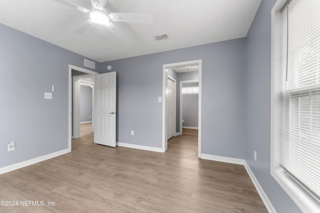 unfurnished bedroom featuring ceiling fan, light hardwood / wood-style floors, and a textured ceiling