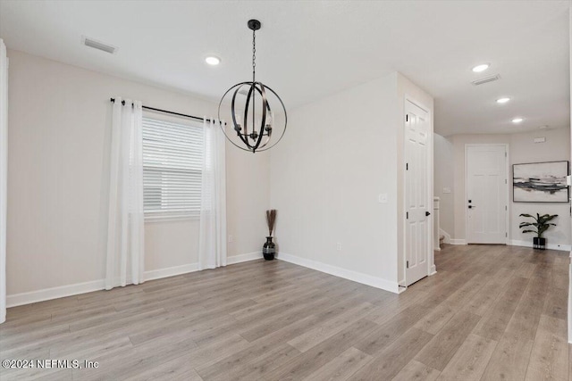 unfurnished dining area with light hardwood / wood-style floors and an inviting chandelier