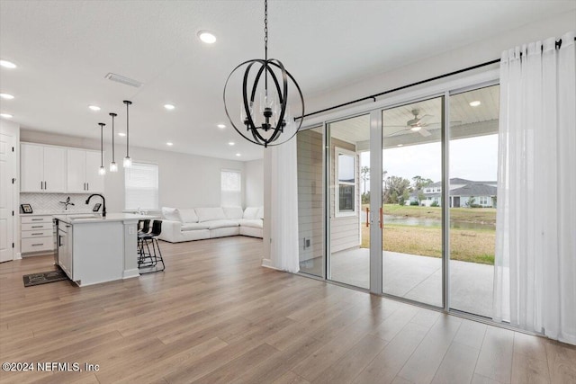 interior space with light wood-type flooring, sink, and an inviting chandelier