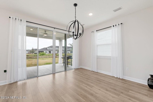 unfurnished dining area featuring light hardwood / wood-style floors and a notable chandelier