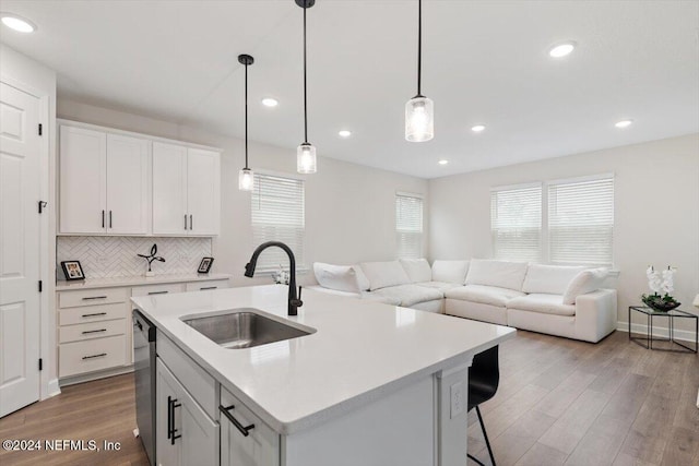 kitchen featuring white cabinetry, a center island with sink, stainless steel dishwasher, and sink