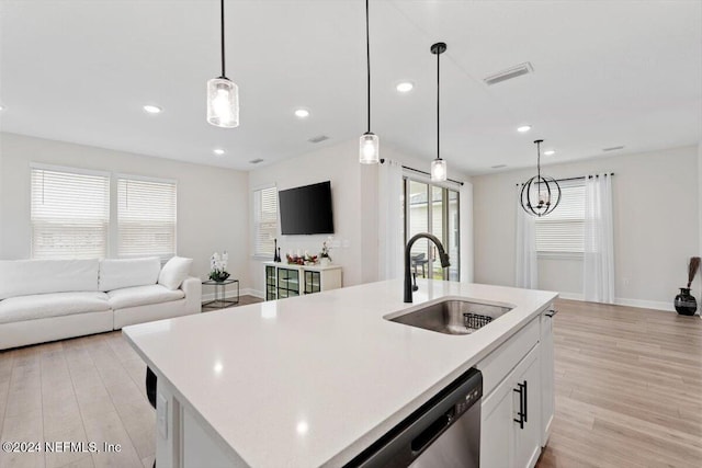 kitchen featuring a kitchen island with sink, white cabinetry, sink, and hanging light fixtures