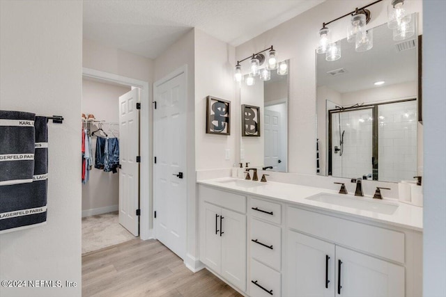 bathroom with a shower with door, vanity, a textured ceiling, and hardwood / wood-style flooring