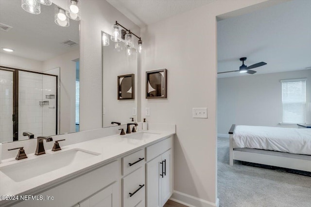 bathroom with ceiling fan, vanity, a shower with shower door, and a textured ceiling