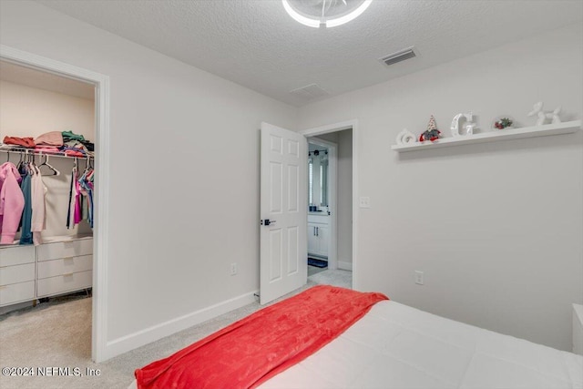 carpeted bedroom featuring a walk in closet, a textured ceiling, and a closet