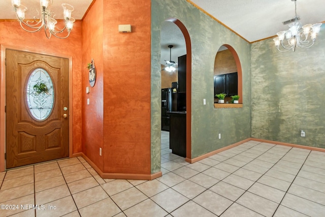 foyer featuring ceiling fan with notable chandelier, light tile patterned floors, and ornamental molding