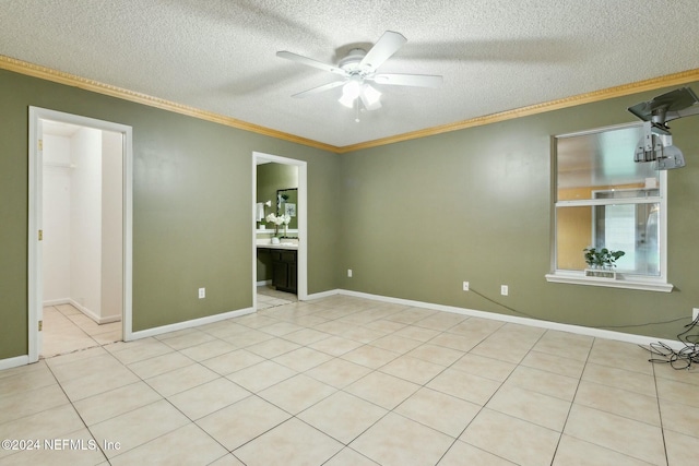 unfurnished bedroom with ensuite bathroom, a textured ceiling, ceiling fan, crown molding, and light tile patterned flooring