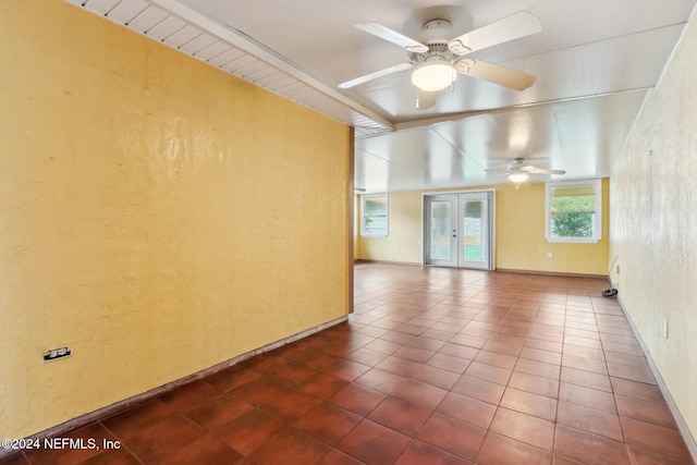 tiled spare room featuring ceiling fan and french doors