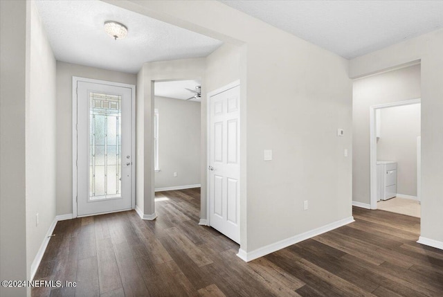 foyer entrance with ceiling fan, dark hardwood / wood-style flooring, a textured ceiling, and washer / dryer