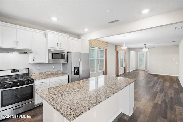 kitchen featuring ceiling fan, white cabinets, light stone counters, a kitchen island, and appliances with stainless steel finishes