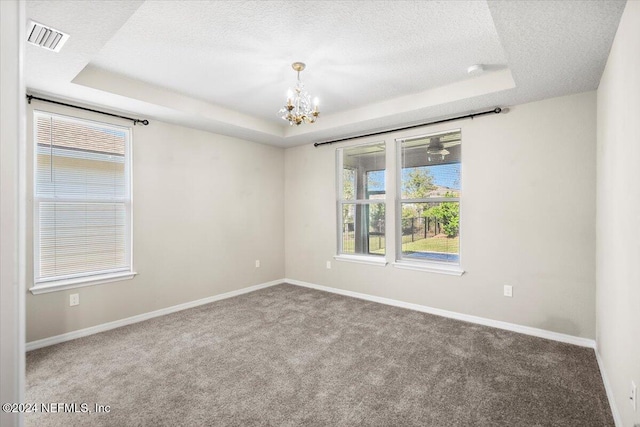 empty room with carpet, a raised ceiling, a textured ceiling, and a chandelier