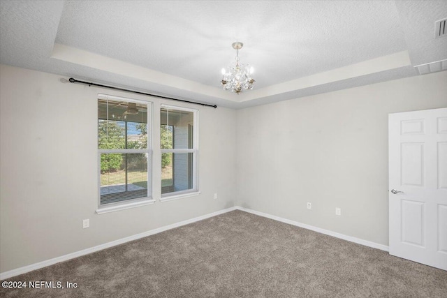 carpeted spare room with a notable chandelier, a textured ceiling, and a tray ceiling