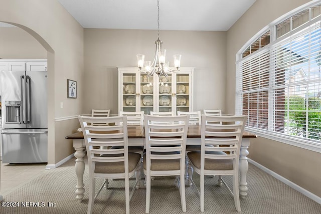 dining area featuring a notable chandelier and light carpet