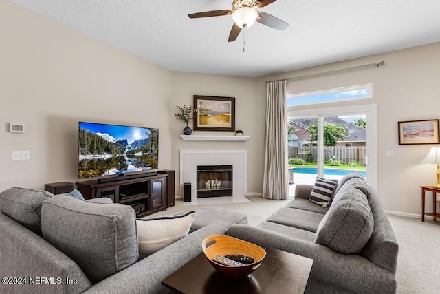 carpeted living room with ceiling fan and a fireplace