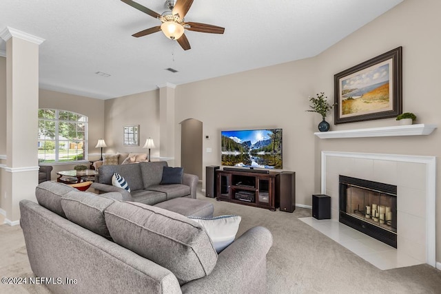 living room featuring a tile fireplace, light colored carpet, and ceiling fan