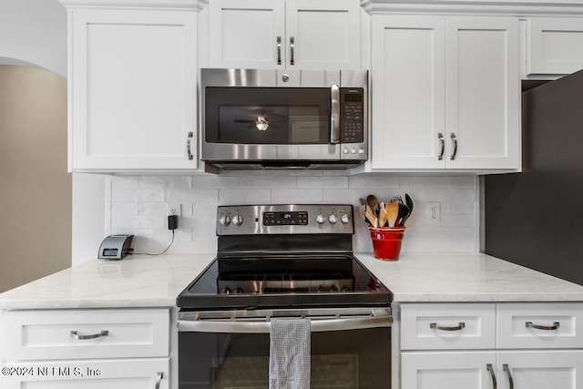 kitchen with light stone countertops, decorative backsplash, white cabinets, and stainless steel appliances