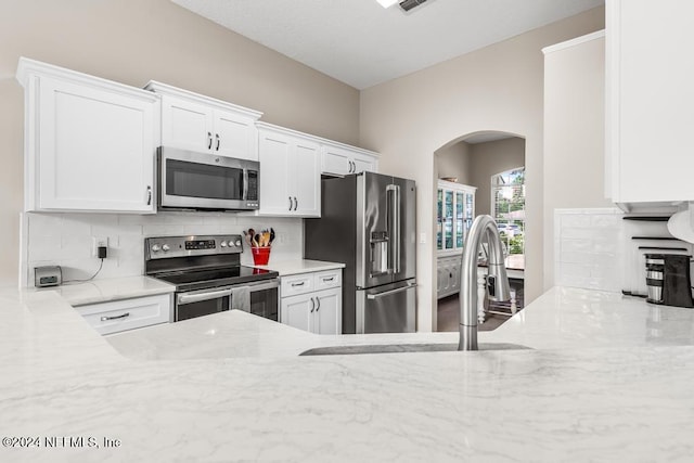 kitchen featuring decorative backsplash, light stone counters, white cabinetry, and stainless steel appliances