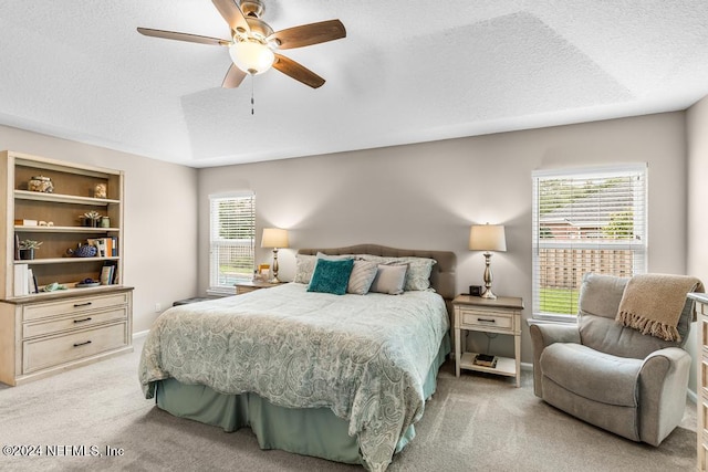 carpeted bedroom with ceiling fan and a textured ceiling