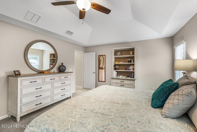 bedroom featuring light carpet, a textured ceiling, a raised ceiling, and ceiling fan