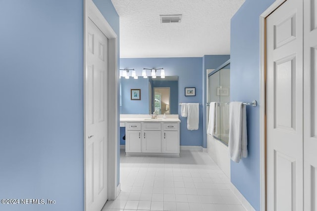 bathroom with tile patterned floors, vanity, shower / bath combination with glass door, and a textured ceiling