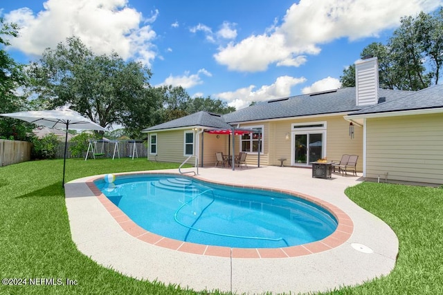 view of pool with a playground, a fire pit, a patio area, and a yard