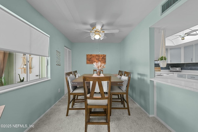 dining area with ceiling fan and light colored carpet